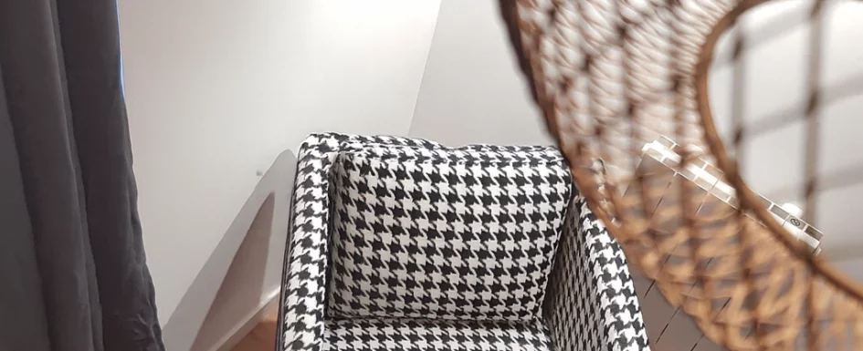 Fauteuil design en tissu motif pied-de-poule noir et blanc dans un salon moderne avec parquet et tapis rond gris