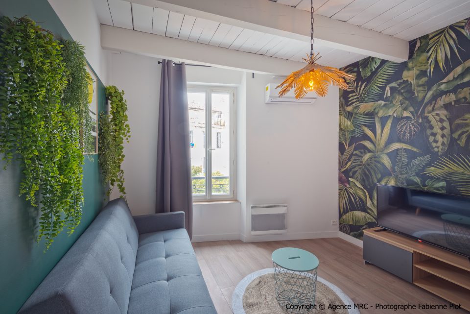 Végétaux synthétiques retombants sur mur vert, décoration botanique intérieure dans un salon rénové