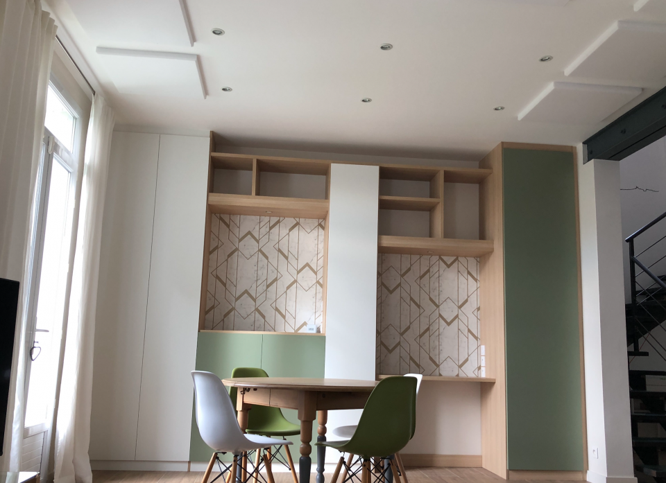 Bureau sur mesure intégré dans un salon avec rangements, fond papier peint géométrique et verrière