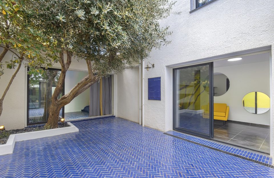 Patio avec carrelage zellige bleu posé en chevrons et fauteuil jaune, association complémentaire bleu jaune extérieur