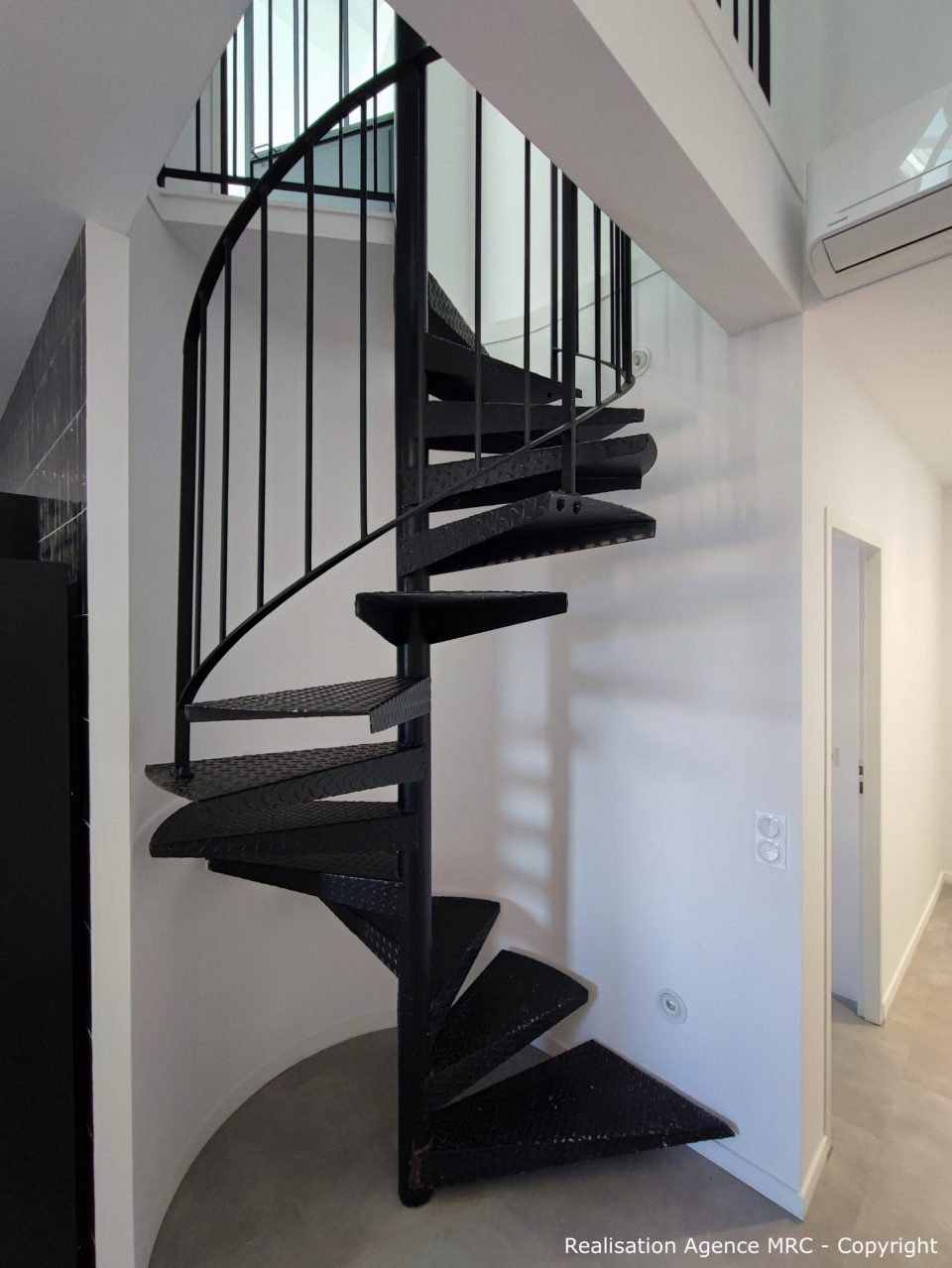 Escalier colimaçon métal noir RAL 9005 avec garde-corps centré, loft contemporain