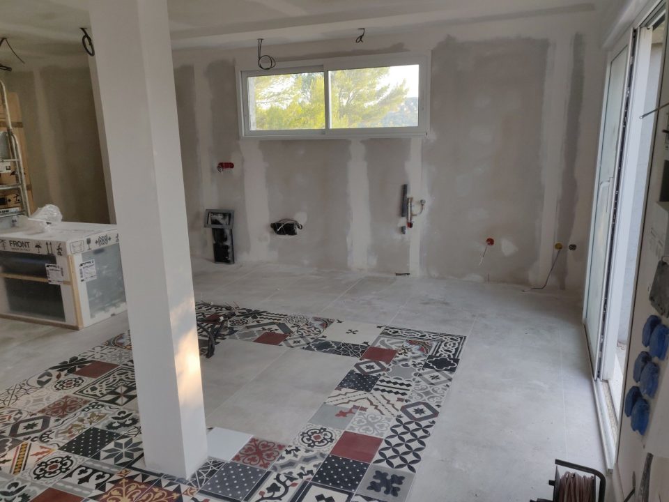 chantier avec poteau coffré et carrelage graphique au sol dans cuisine