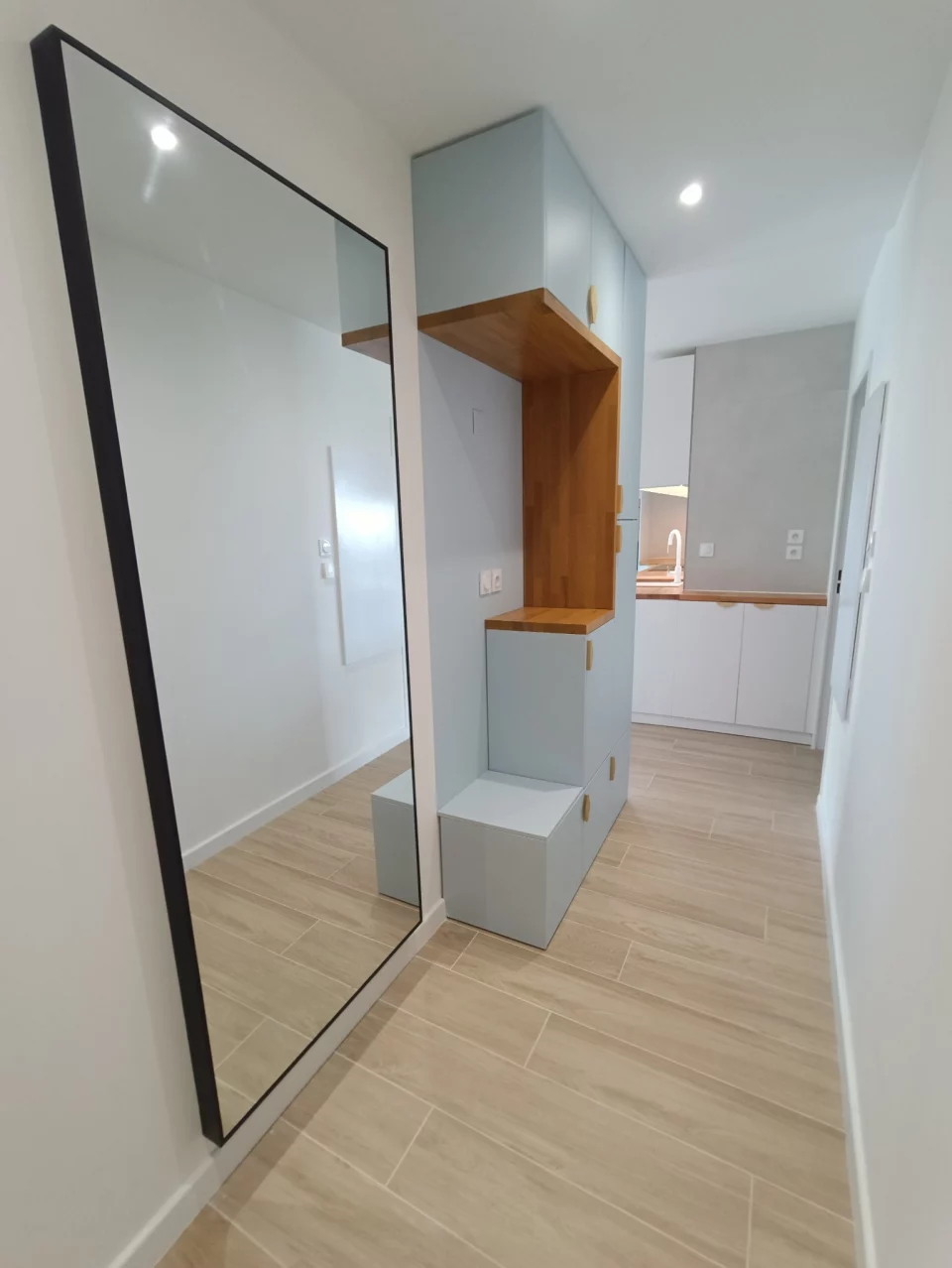 Entrée sur mesure après travaux avec miroir et banc bois, finitions soignées couloir