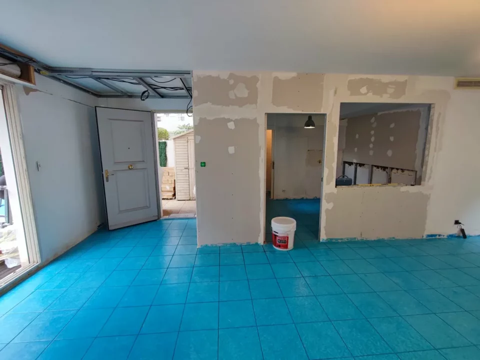 état initial appartement avant travaux, espace entrée non délimité, carrelage beige et porte d'entrée existante