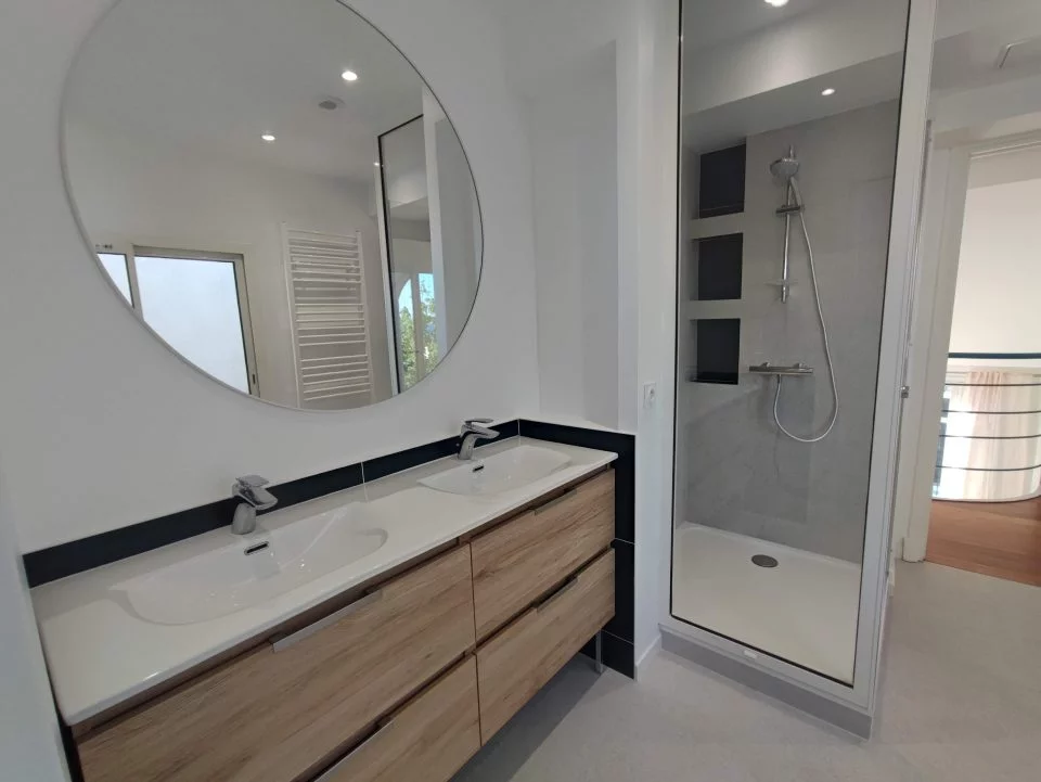 After renovation: 55 in double vanity with deep blue tile surround and full-height mirror
