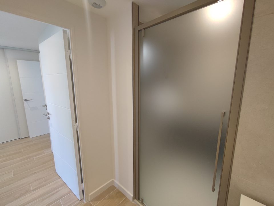Salle de bain après rénovation : grande douche avec niches carrelées, meuble vasque effet bois et sol parquet