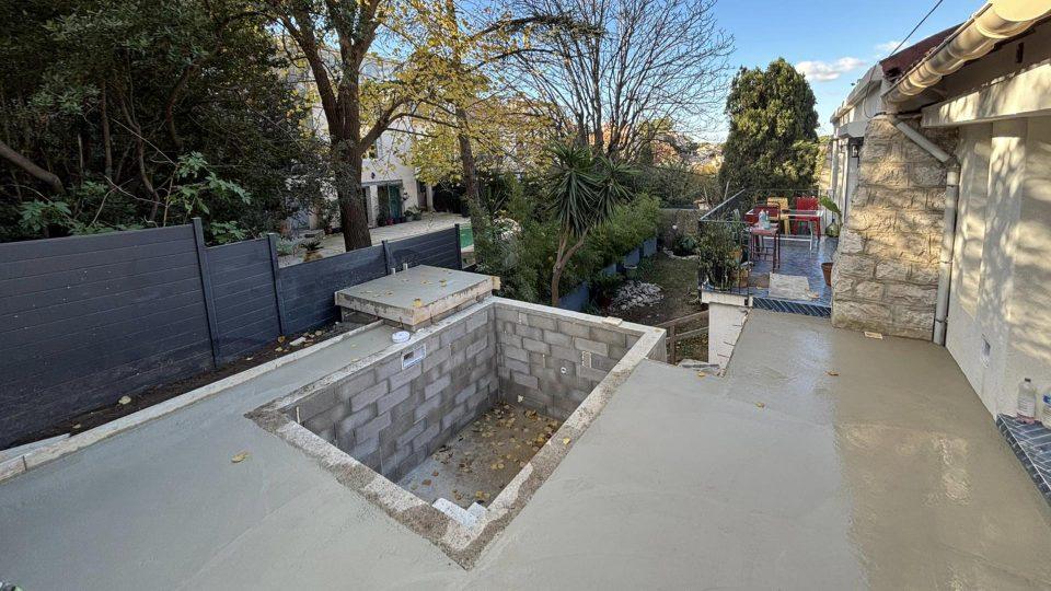 Avant-après du chantier : bassin maçonné de moins de 10 m² avec travertin au sol, enduit en cohérence avec la maison et touches de bejmat